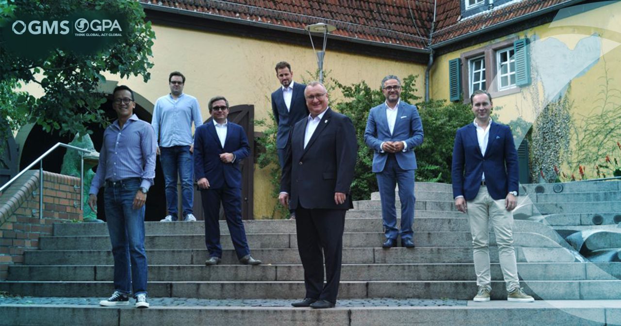 Eine Gruppe Männer steht auf Stufen vor einem Gebäude.